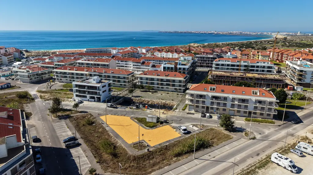 A Consolação vista do ar: casas de telhado vermelho, o areal e o mar, com Peniche ao fundo.